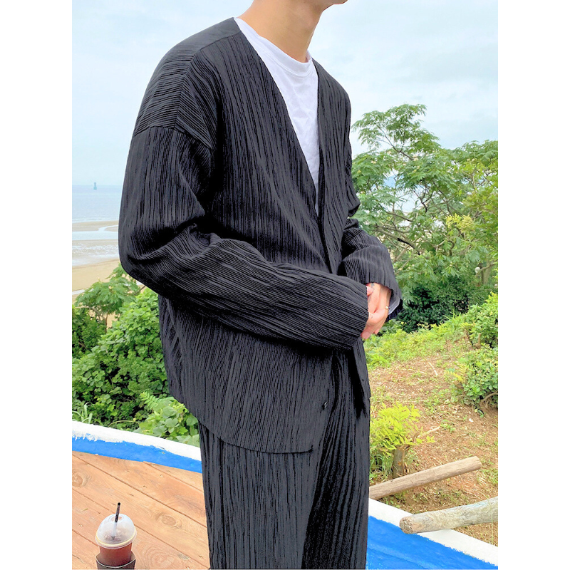 横向きで立つ男性のコーデ全体(プリーツセットアップ)