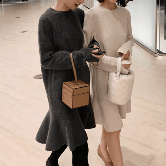 アイボリーのフレアニットワンピースとグレーのフレアニットワンピースを着た女性2人が歩く姿