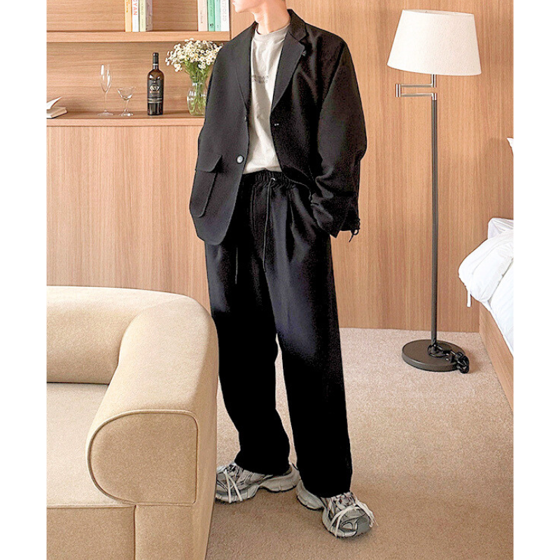 ブラックセットアップを着こなす男性|ドローコード付きジャケットとワイドパンツ