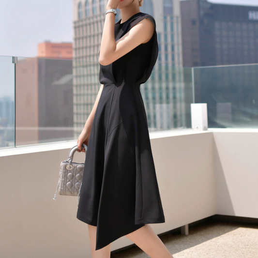 斜めから見たブラックワンピースで、フレア裾の動きとハイウエスト切り替えがスタイルを美しく見せる