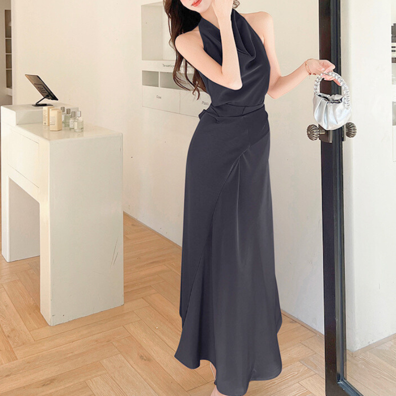 ブラックのシルクワンピースをまとった女性がエントランスでポーズ