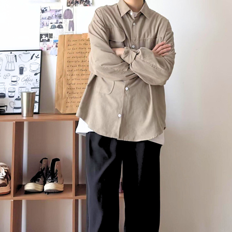 ベージュのワークシャツを腕組みして着る姿