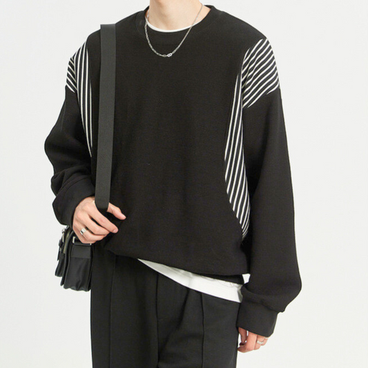 ストライプ切替が映える黒ニットを着用した男性の正面コーデ