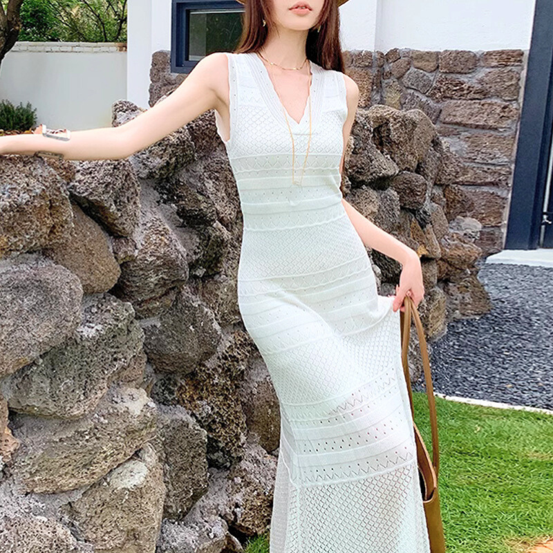 緑と石の背景に白ワンピースが映える大人コーデ