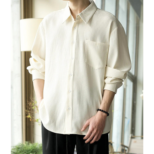 ベージュシャツを袖まくりして立っている男性のコーデ