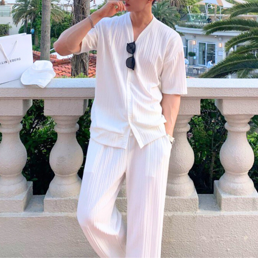 白のプリーツセットアップを着た男性のリゾート風コーデ
