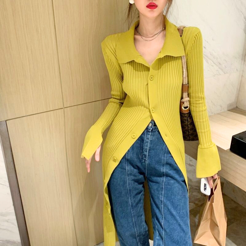 イエローニットシャツを羽織った女性がソファでくつろぐ春のリラックススタイル。