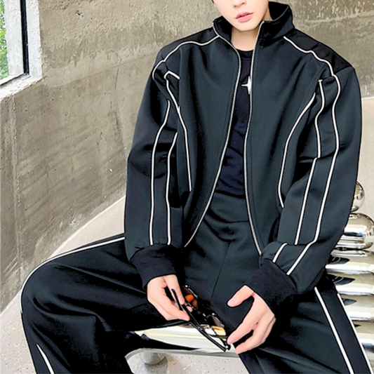 ブラックセットアップを椅子に座って着こなす男性