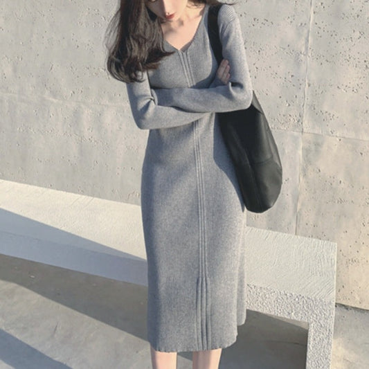 グレーのVネックリブニットワンピースを着用し、顔を隠しながらポーズを取る女性のコーディネート