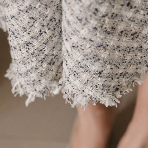 スカート裾のフリンジをクローズアップし、ツイード風生地の上品な質感を強調