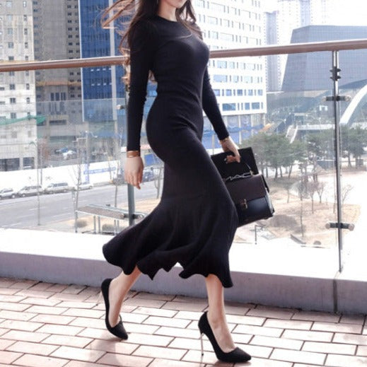 斜めから見たブラックワンピースで、ボディラインに沿ったタイトシルエットと裾フレアを強調