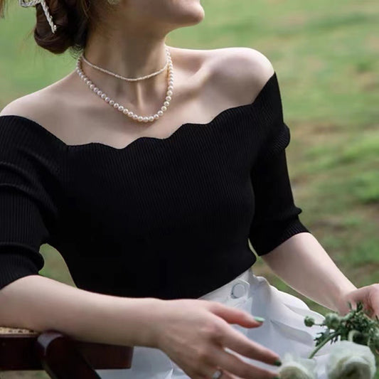 ブラックトップスのデコルテ部分をクローズアップし、肩と鎖骨の肌見せが大人可愛い印象