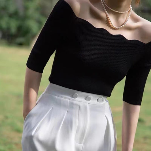 ブラックのスカラップオフショルダーニットトップスを正面から撮影し、落ち着いた色合いで上品な色気を演出