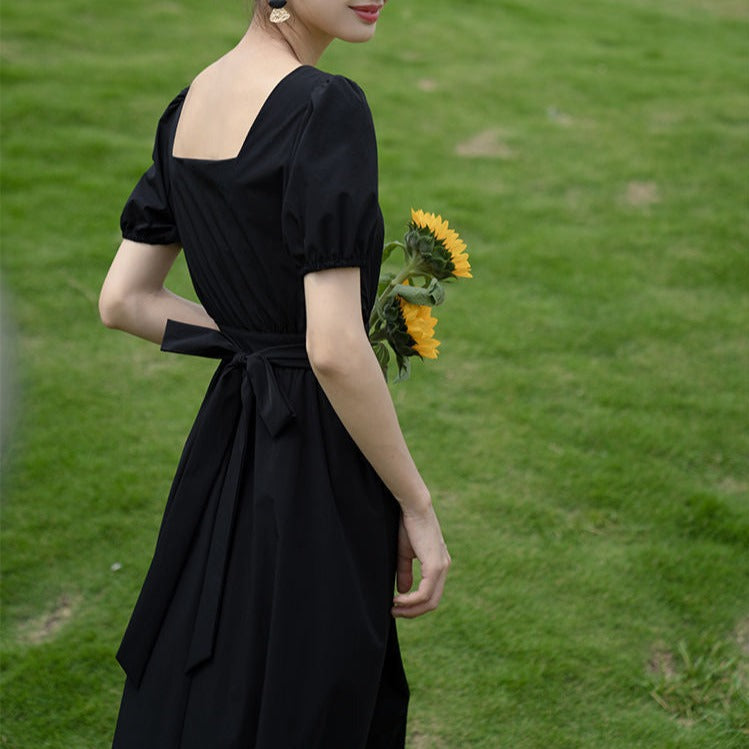 歩いたときに広がるフレアシルエットが美しいブラックワンピースで、サイドの肌見せがチラリ