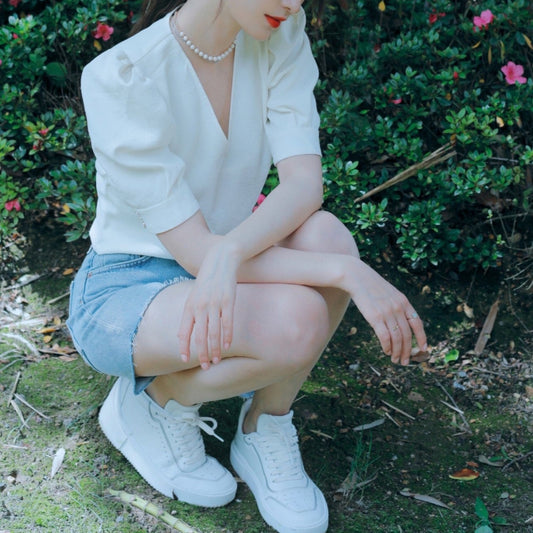 チェアや地面に座り、パフスリーブの華やかさとVネックの上品さを強調したリラックスショット