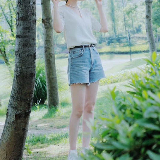 デニムショートパンツと合わせたカジュアルコーデで、ホワイトブラウスの清楚感と抜け感を両立