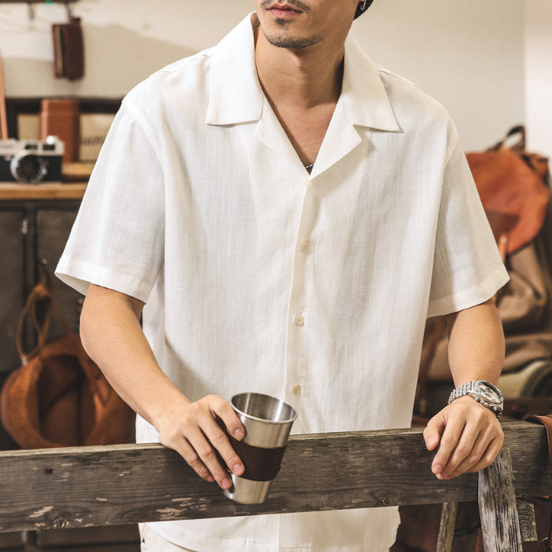 アイボリーのオープンカラー半袖シャツをカップと合わせた男性の上半身コーデ