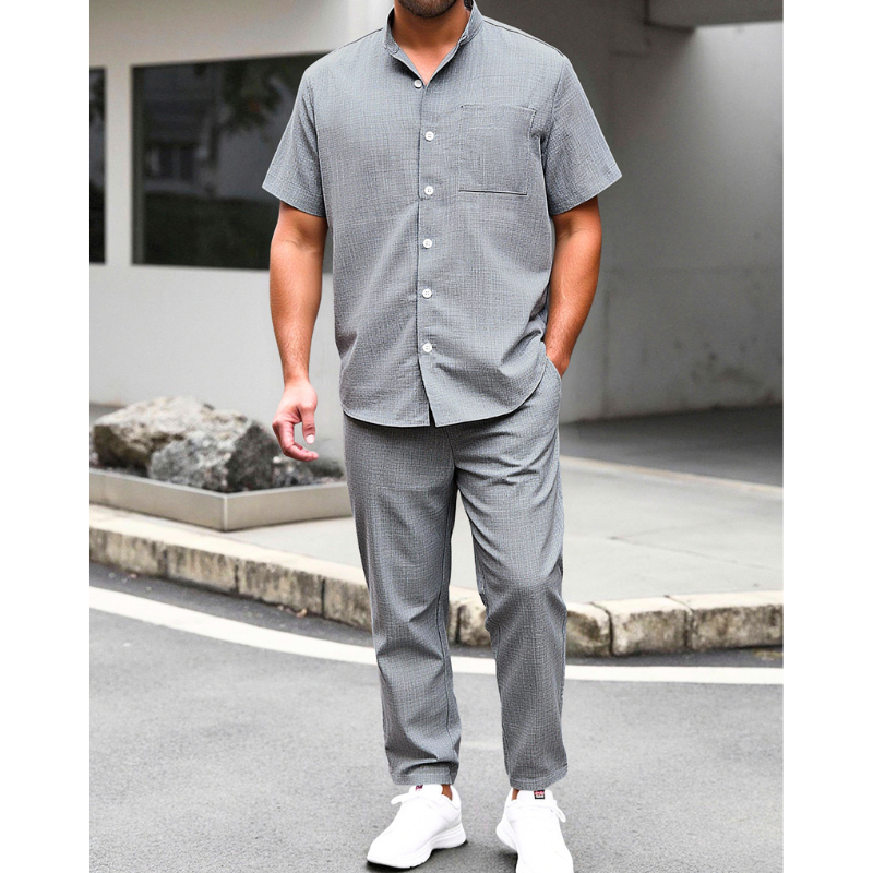 グレーのリネンライクバンドカラーシャツとイージーパンツセットアップを着た男性の夏コーデ