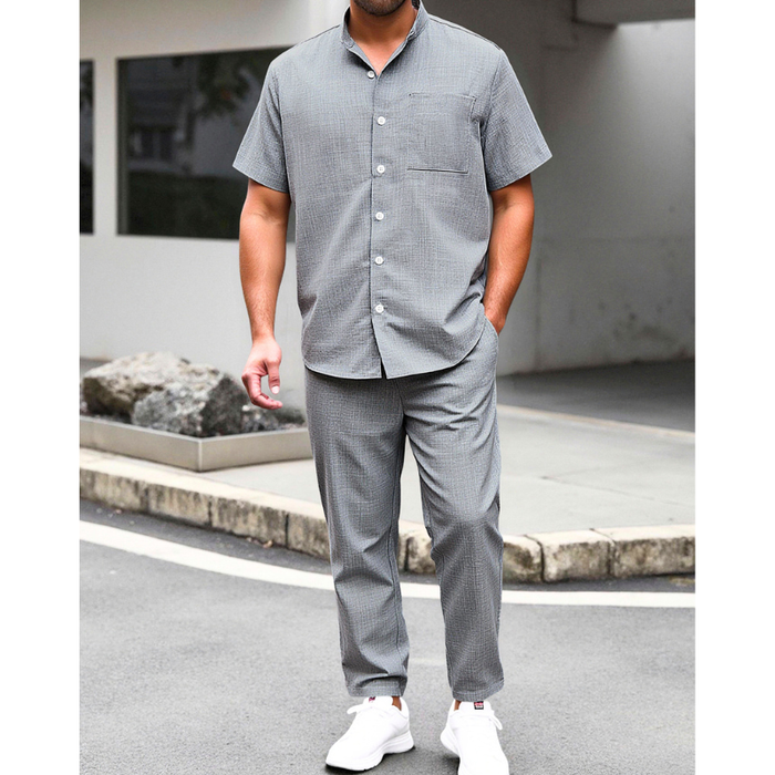 グレーのリネンライクバンドカラーシャツとイージーパンツセットアップを着た男性の夏コーデ