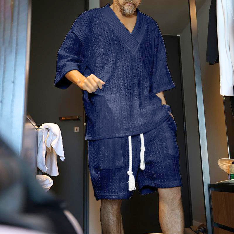 ネイビーの立体編みVネックニットセットアップを着た男性の夏コーデ