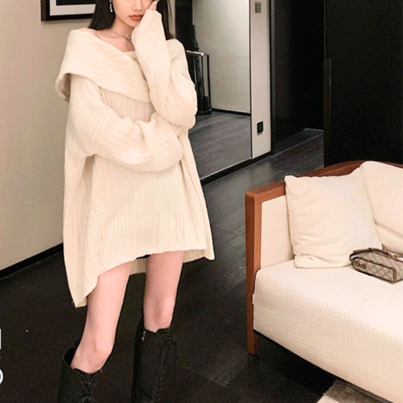 アイボリーのニットワンピースを着用した女性の正面。鏡の前での長袖と裾のシルエットが分かる写真