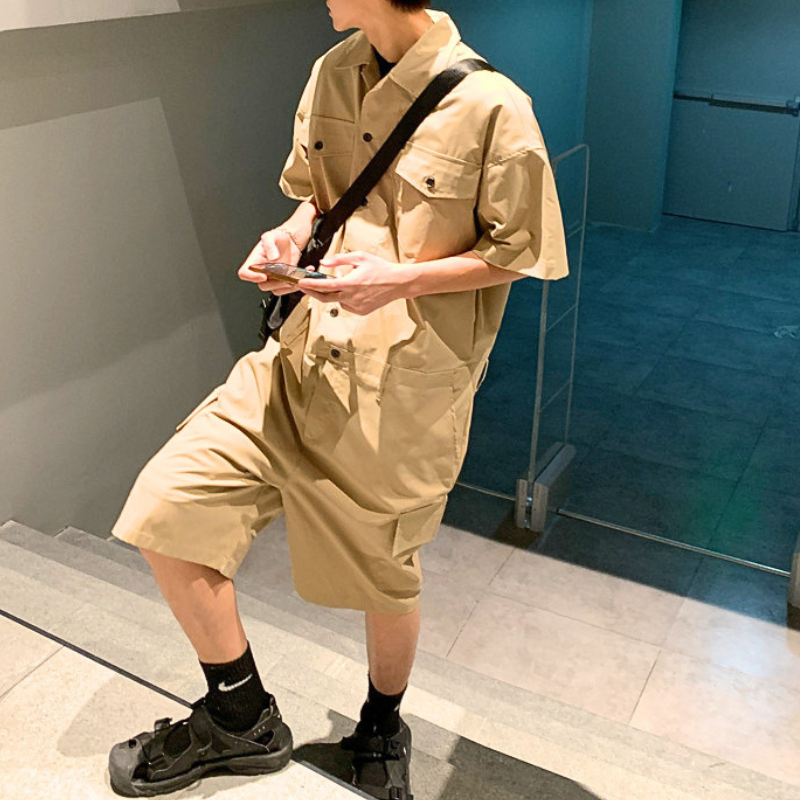 ベージュの半袖カーゴジャンプスーツを階段で着た男性の横向きコーデ