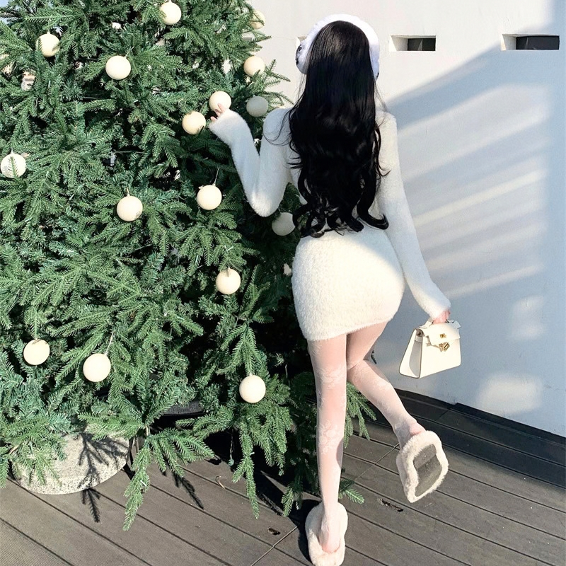ホワイトのシャギーニットセットアップ。クリスマスツリーの横で後ろを向いて歩く全身。長袖トップスとミニスカート