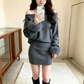 グレーのワンショルダーニットミニワンピースを着た女性の鏡越しの正面。袖口と黒いロングブーツが見える
