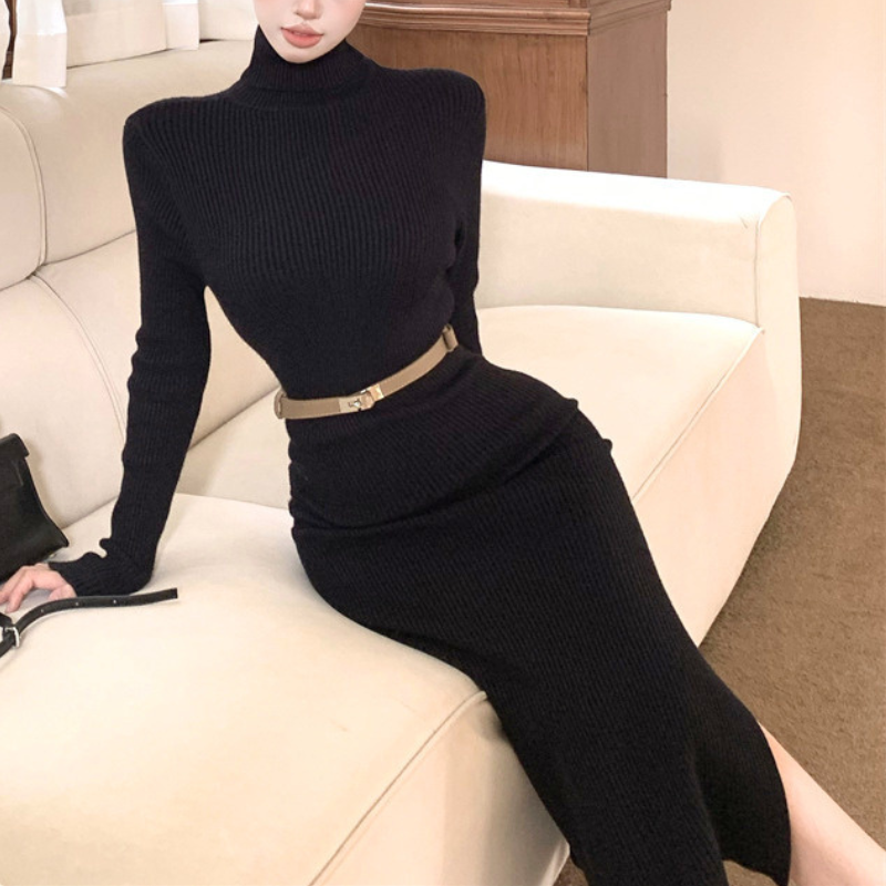 ブラックのベルト付きハイネックタイトニットワンピース。女性がソファに座った着用姿。長い袖と腰を区切るベルト、タイトな黒い身頃