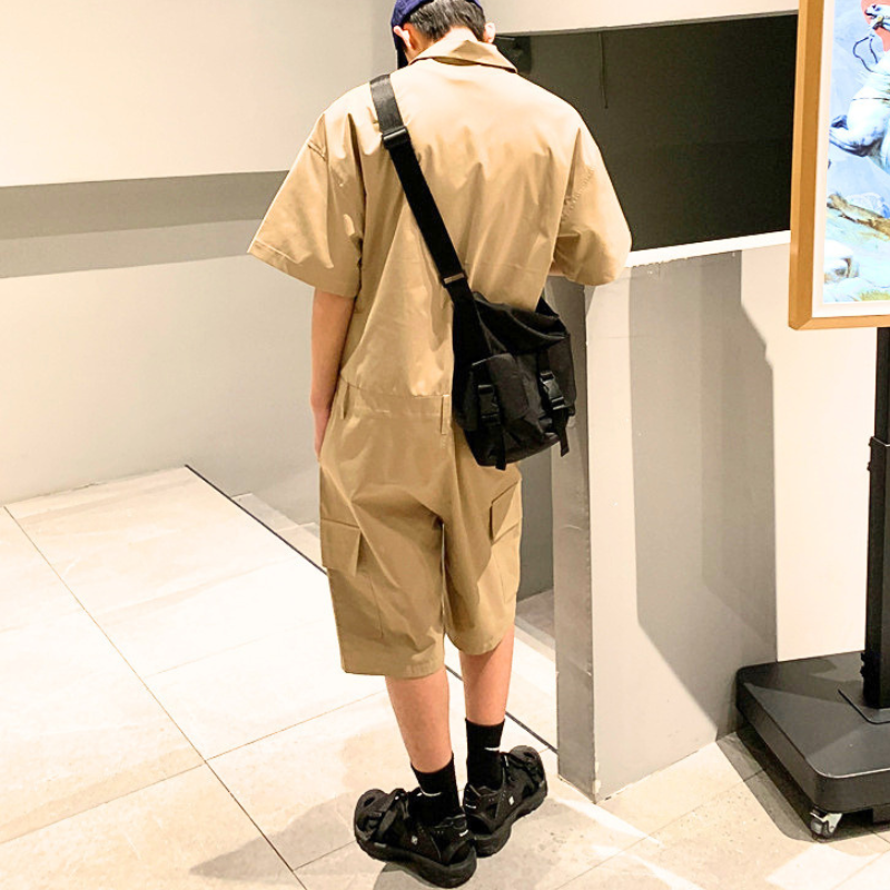 ベージュの半袖カーゴジャンプスーツをバッグと合わせた男性の背面コーデ