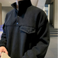 ブラックのスタンドカラープルオーバーとワイドパンツのセットアップを着た男性。立ち襟と胸の横切り替え、フラップ型ポケットを斜めから大きく写した姿