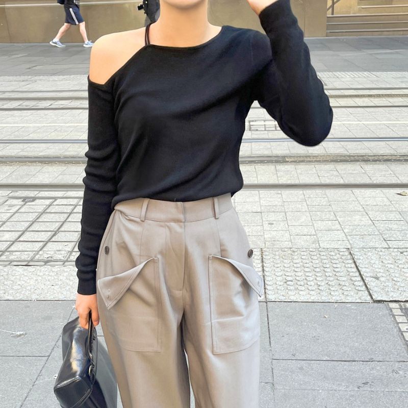 ブラックの肩見せニットトップスを着用した立ち姿の全身コーデ