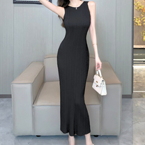 ブラックのリブニットワンピースを着用し室内でポージングする女性