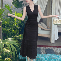 黒ワンピースを着てナチュラルウッド前に佇む女性