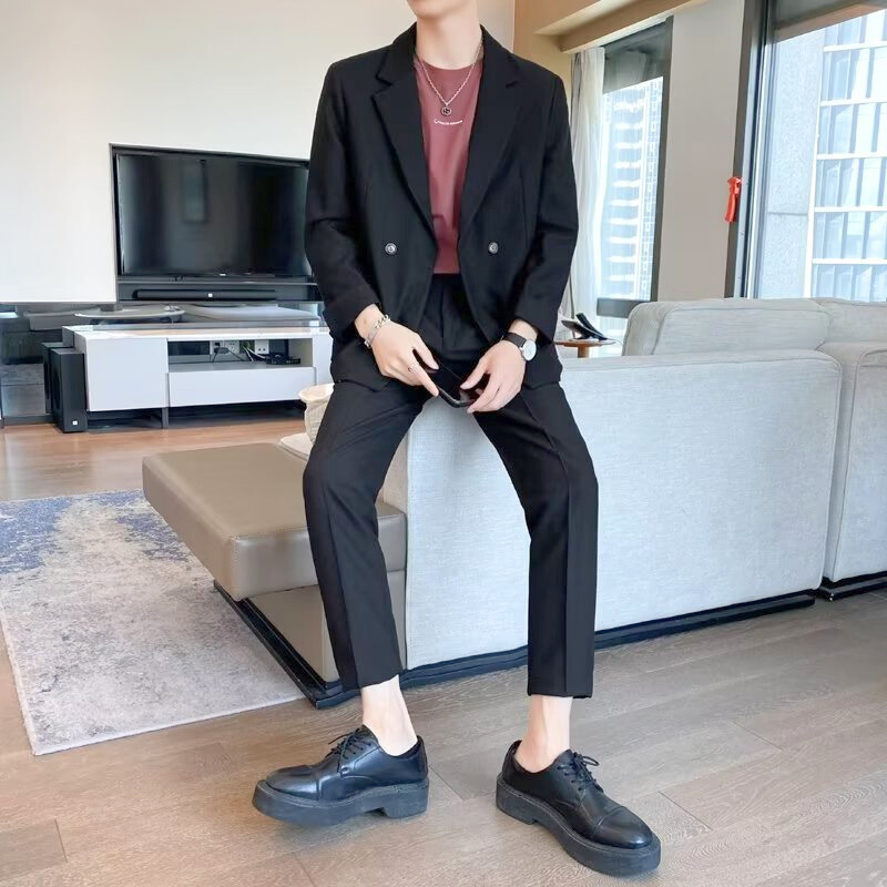 ブラックセットアップで大人のきれいめコーデをした男性がソファに座る姿