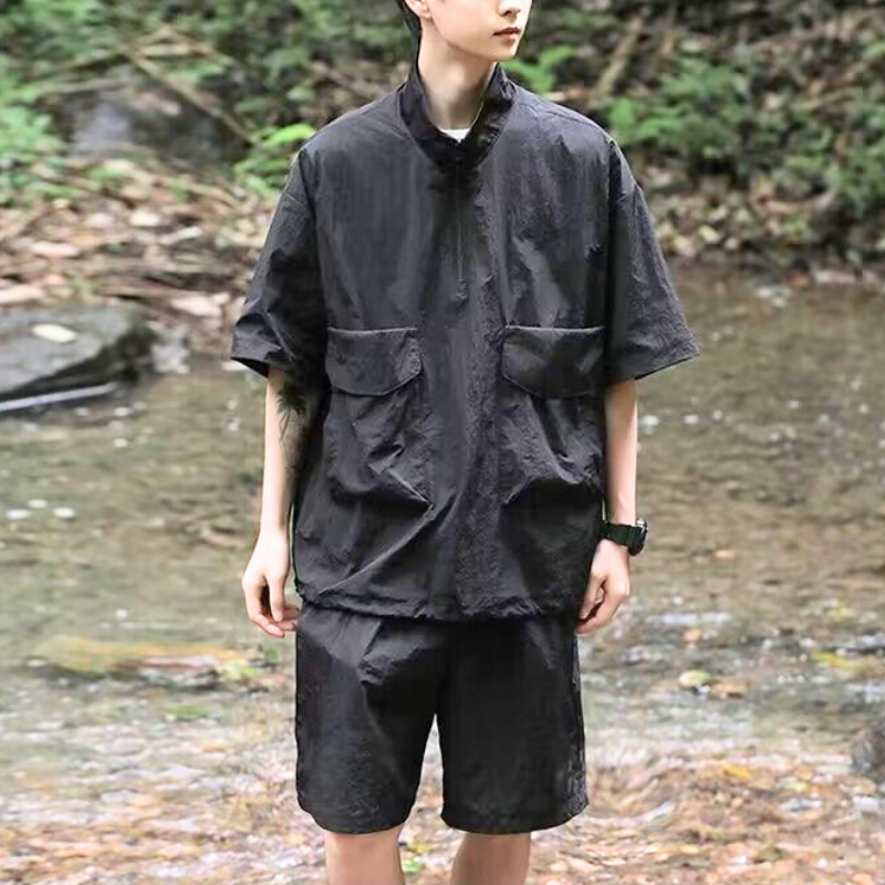 黒の撥水セットアップを着用し、森の中を歩く男性
