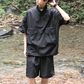 黒の撥水セットアップを着用し、川遊びを楽しむ男性