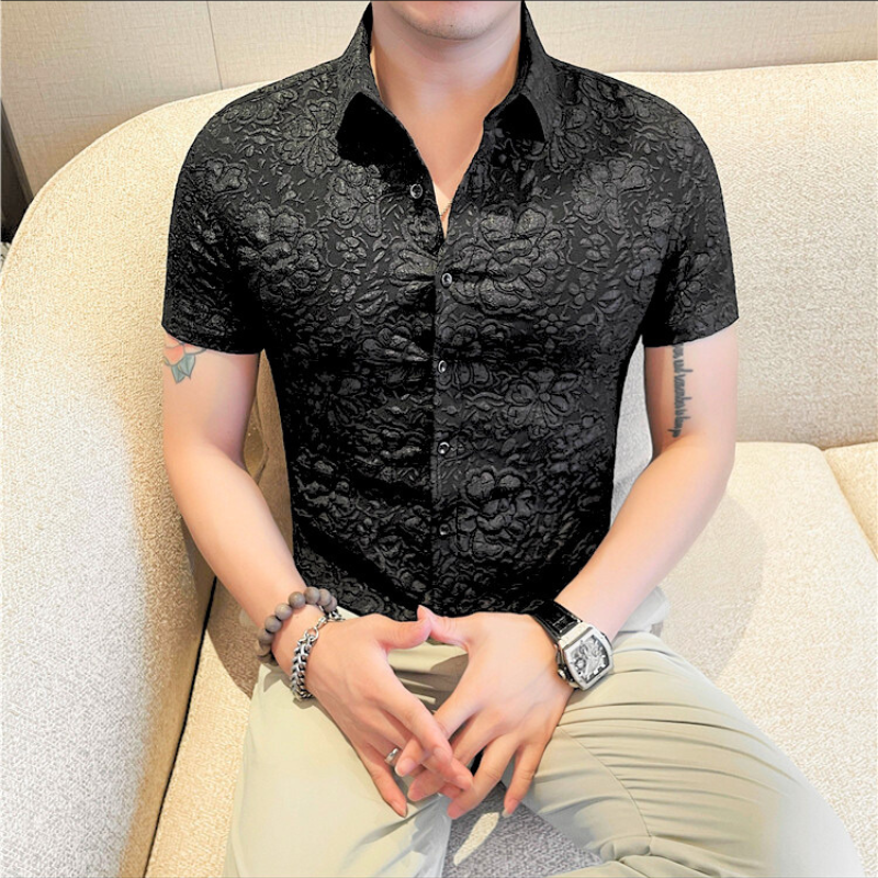 黒の総柄シャツを着た男性がソファに座って落ち着いた雰囲気