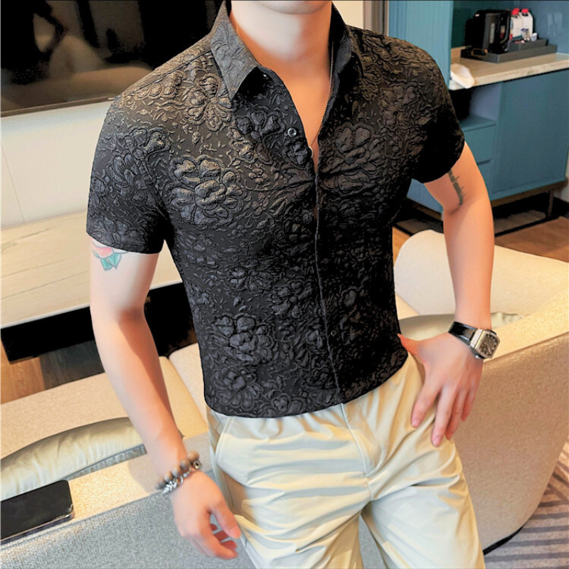 ブラックの花柄シャツを着た男性が腕を腰にあて立っているポーズ