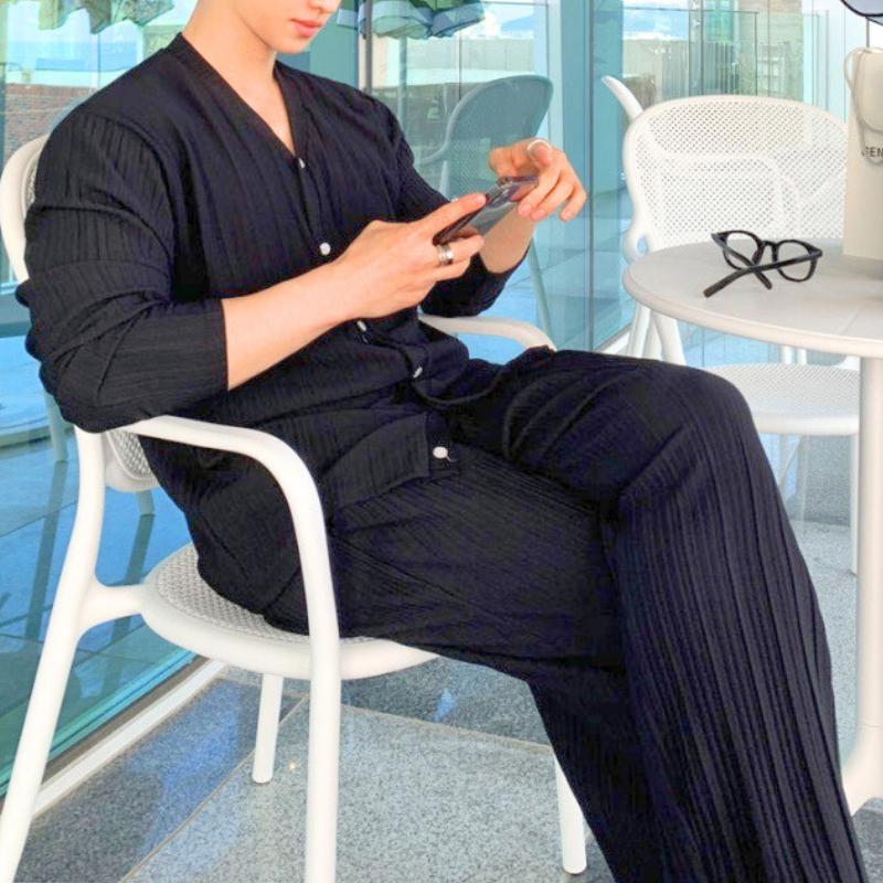 カフェシーンでスマホを見る黒コーデ男性