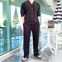 黒プリーツセットアップを着た立ち姿の男性