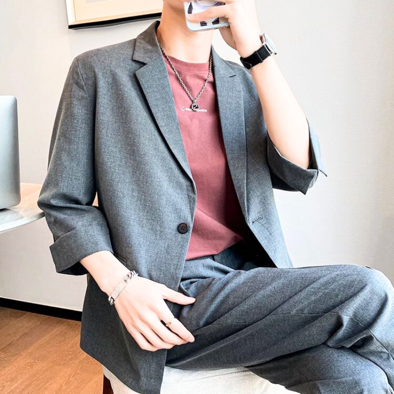 チャコールセットアップで脚を組んで座るおしゃれな着こなし