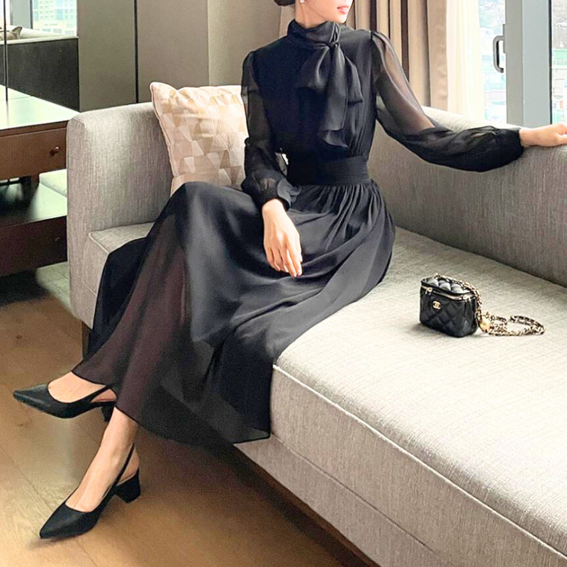 ブラックワンピースをソファで上品に着こなす女性