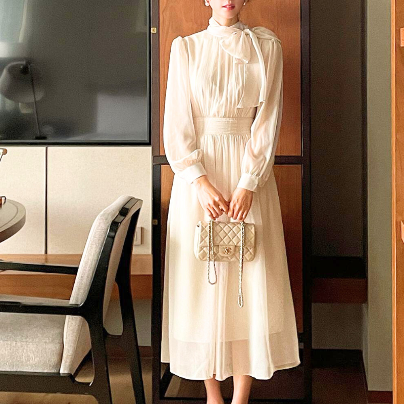 アイボリーのシフォンワンピースを正面から着用する女性