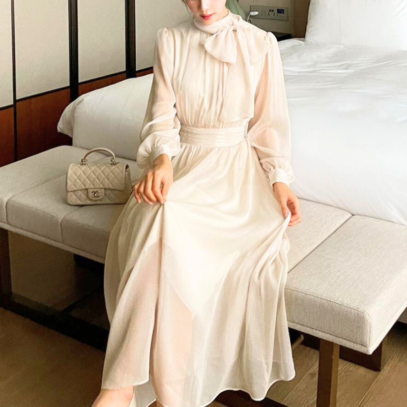 ソファに座りシフォンワンピースを着用する女性