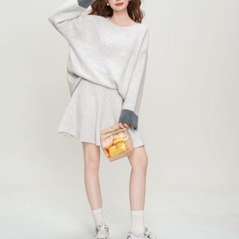 アイボリーの配色袖ニットセットアップの立ち姿コーデ