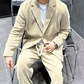 ベージュのセットアップで椅子に座る男性 正面