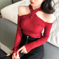 レッドの肩見せリブニットトップスを座って着用したコーデ