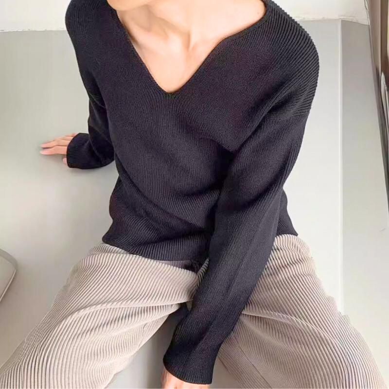 ブラックニットを着た男性の座り姿、モードな印象