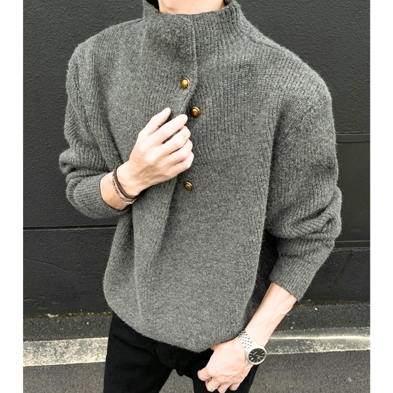 グレーニットを着た男性が横向きの姿勢で立つコーデ写真